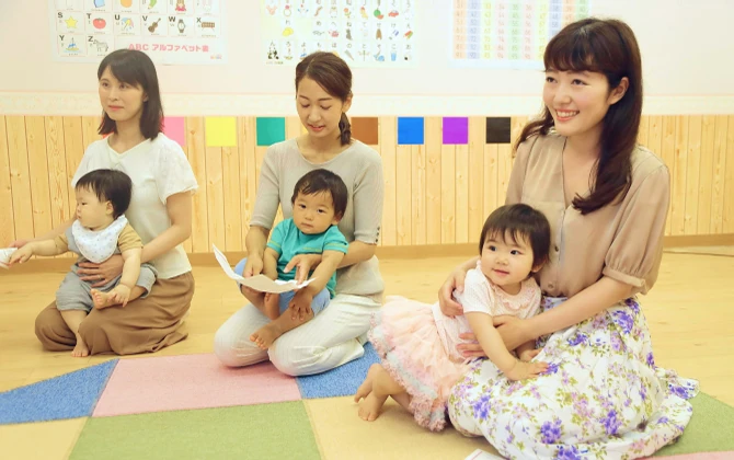教室内で複数の母子が横並びで座りそれぞれの赤ちゃんを抱いている様子