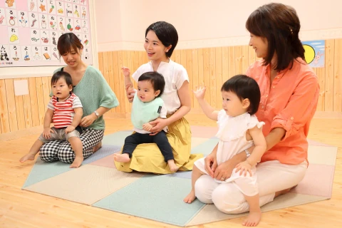 教室内で複数の母子が並んで座り先生と一緒に過ごす様子