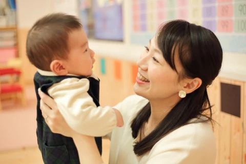 先生が赤ちゃんを抱き上げ目を合わせて笑いかける様子